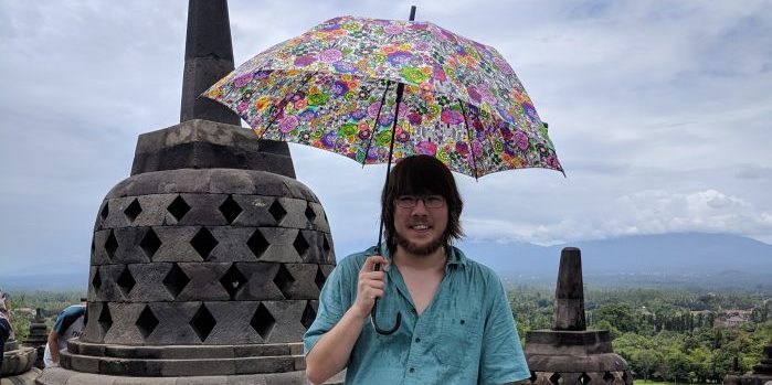 Erik standing with an umbrella on a temple near Yogyakarta, IN.
